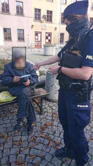 Jeleniogórska policjantka przekazuje maseczkę bezdomnemu mężczyźnie.