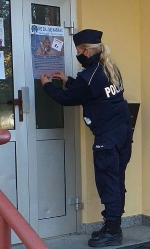 Policjantka umieszcza materiały prewencyjne informujące o sposobach działania oszustów na szkodę seniorów na klatkach schodowych oraz tablicach ogłoszeniowych bloków mieszkalnych na terenie osiedla Zabobrze w Jeleniej Górze