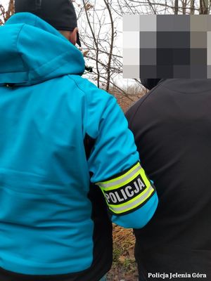 Policjant prowadzi zatrzymanego mężczyznę