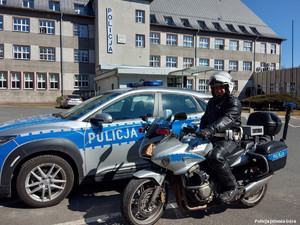 Policjant jeleniogórskiej drogówki na motocyklu obok radiowozu