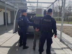 Policjanci z zatrzymanym przed radiowozem