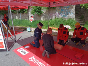 Policjanci, strażacy , kierowca podczas pokazu udzielania pierwszej pomocy