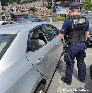 policjant przy samochodzie z wybitą szybą