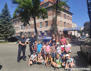 Dzieci wraz z policjantkami i opiekunem przed komisariatem