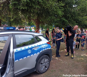 Radiowóz, policjantka i uczestnicy festynu