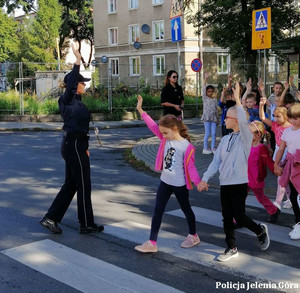 Policjantka z dziećmi ćwiczy przechodzenie przez jezdnię