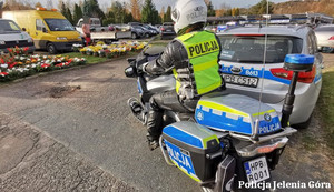 Policjant na motocyklu przed cmentarzem