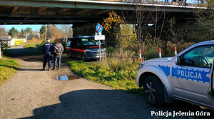 Policjant z zatrzymanym, radiowóz w tle