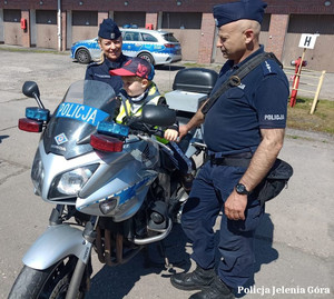 Dziecko na policyjnym motocyklu, obok funkcjonariusze