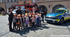 Policjanci z dziećmi, w tle policyjny radiowóz