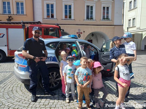 Policjanci z dziećmi obok radiowozu