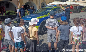 Policjanci z dziećmi, w tle radiowóz