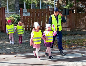 Policjantka z dziećmi w ramach Bezpiecznej drogi do szkoły