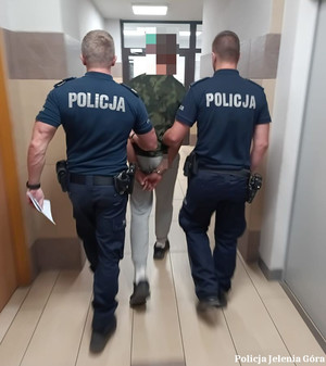 Policjanci prowadzą zatrzymanego