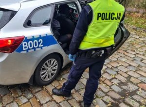 Radiowóz policyjny , a przed nim policjant