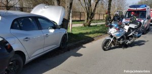 Pojazd Renault po uderzeniu w drzewo, obok policyjne motocykle, w tle policjanci