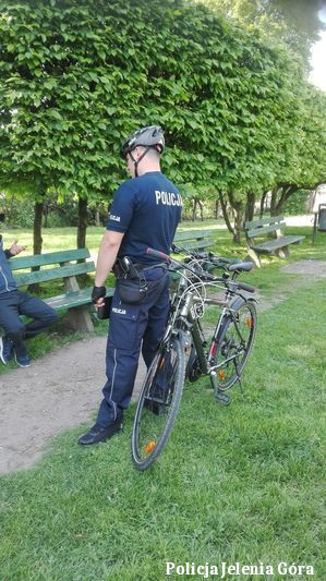 Policjant  w patrolu rowerowym w  parku rozmawia z mieszkańcem