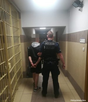 Policjant prowadzi zatrzymanego mężczyznę