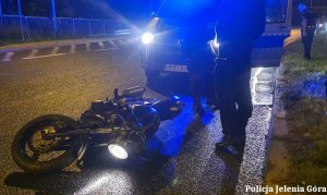 Policjanci, przewrócony na jezdni motocykl oraz policyjny radiowóz